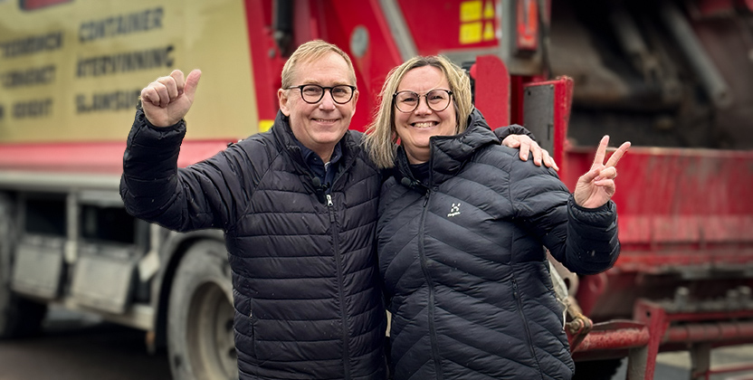 Två personer som står framför en sopbil.