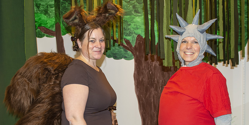 Två kvinnor - del ena utklädd till en brun ekorre med yvig svans och den andra till en ljusgrå igelkott med röd tröja och taggar på huvudet.