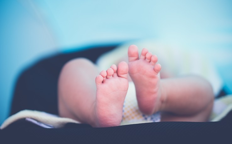 Närbild på en babys fötter med suddig bakgrund i blå toner.