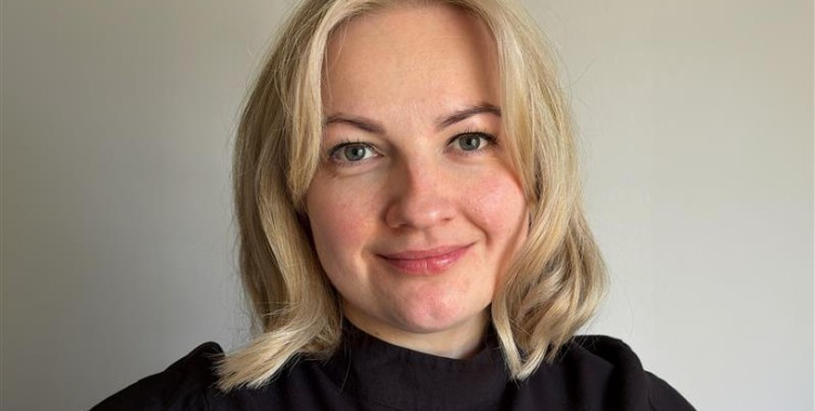 Person med blont axellångt hår och svart tröja, ansiktet är suddat.