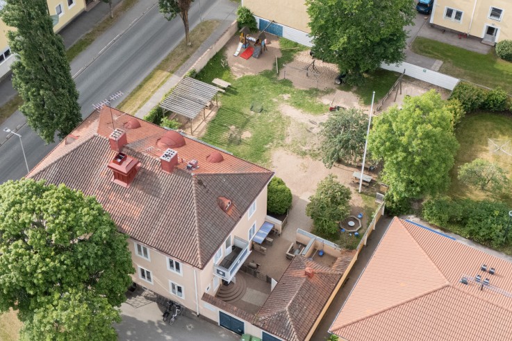 Fågelperspektiv över ett bostadsområde med flerfamiljshus, trädgårdar och gator.